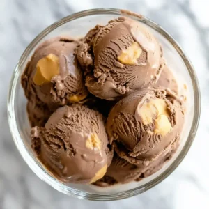 Glass bowl filled with chocolate ice cream and peanut butter swirls.