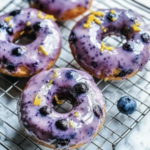 Four blueberry-glazed donuts with purple glaze, zest, and a blueberry