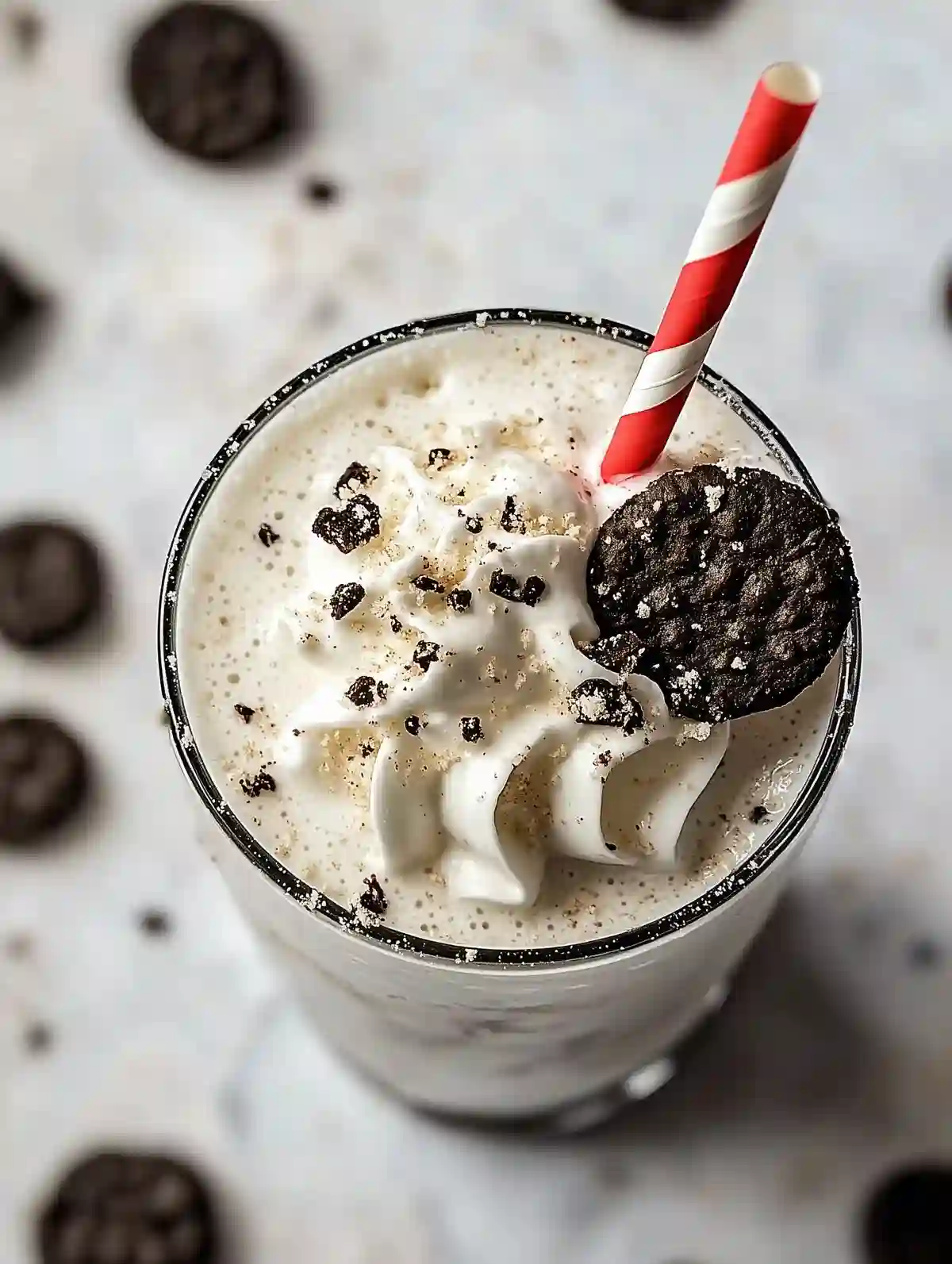Dessert drink with whipped cream, crushed cookies, striped straw on marble