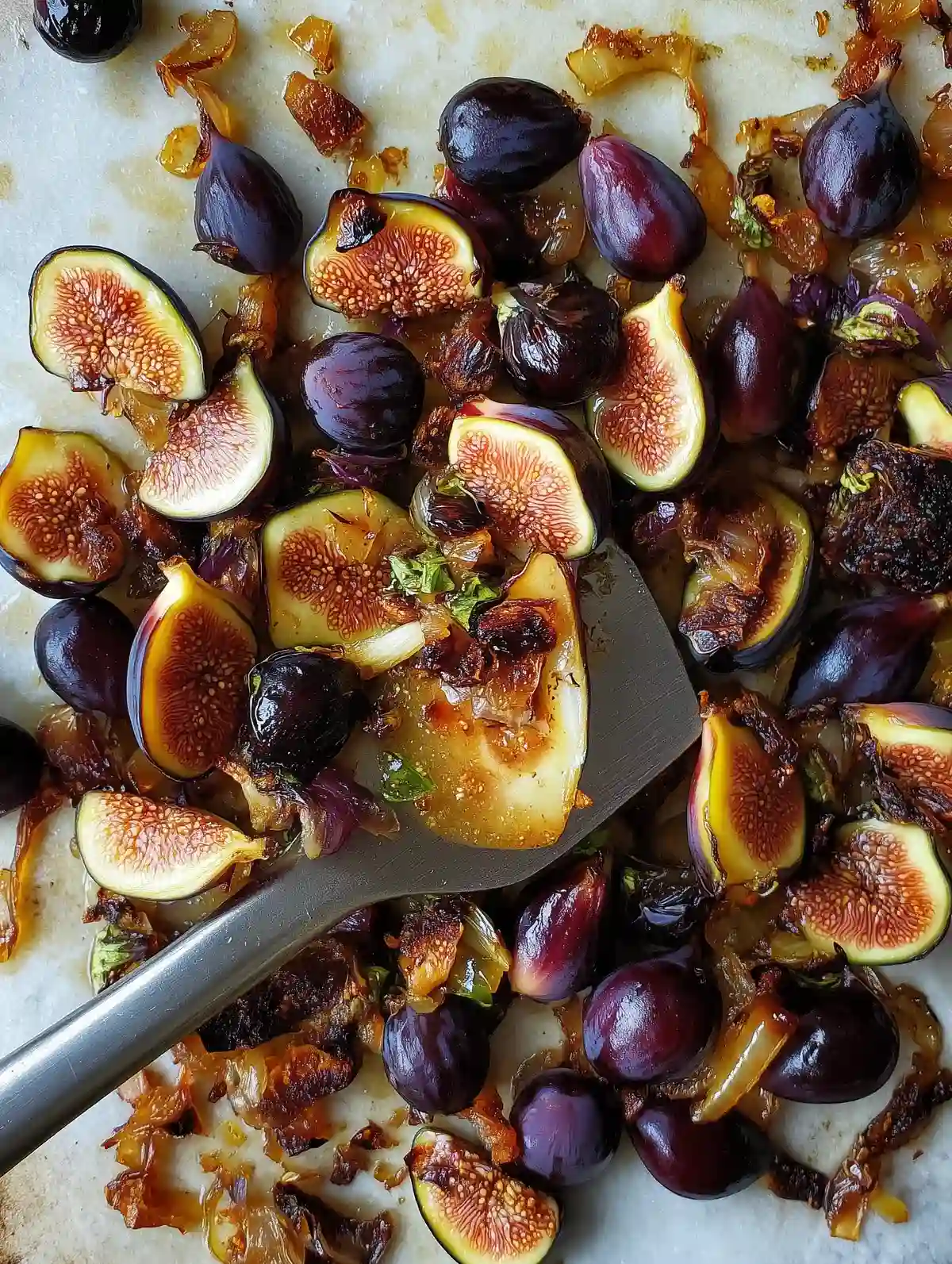 Sautéed figs, grapes, and caramelized onions with a spatula on marble surface