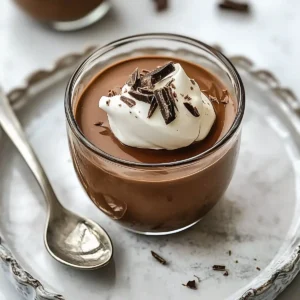 Glass bowl of chocolate pudding topped with whipped cream and shavings.