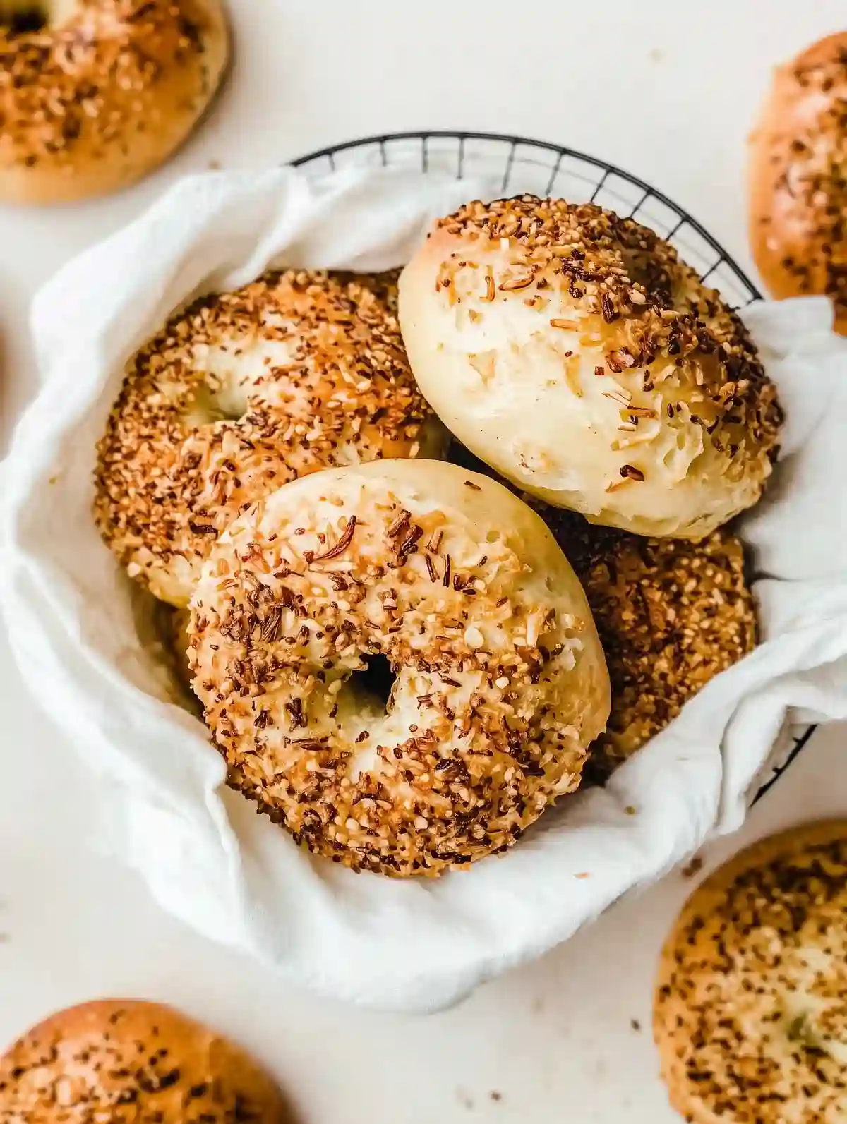 Wire basket with golden brown onion bagels on a marble surface.