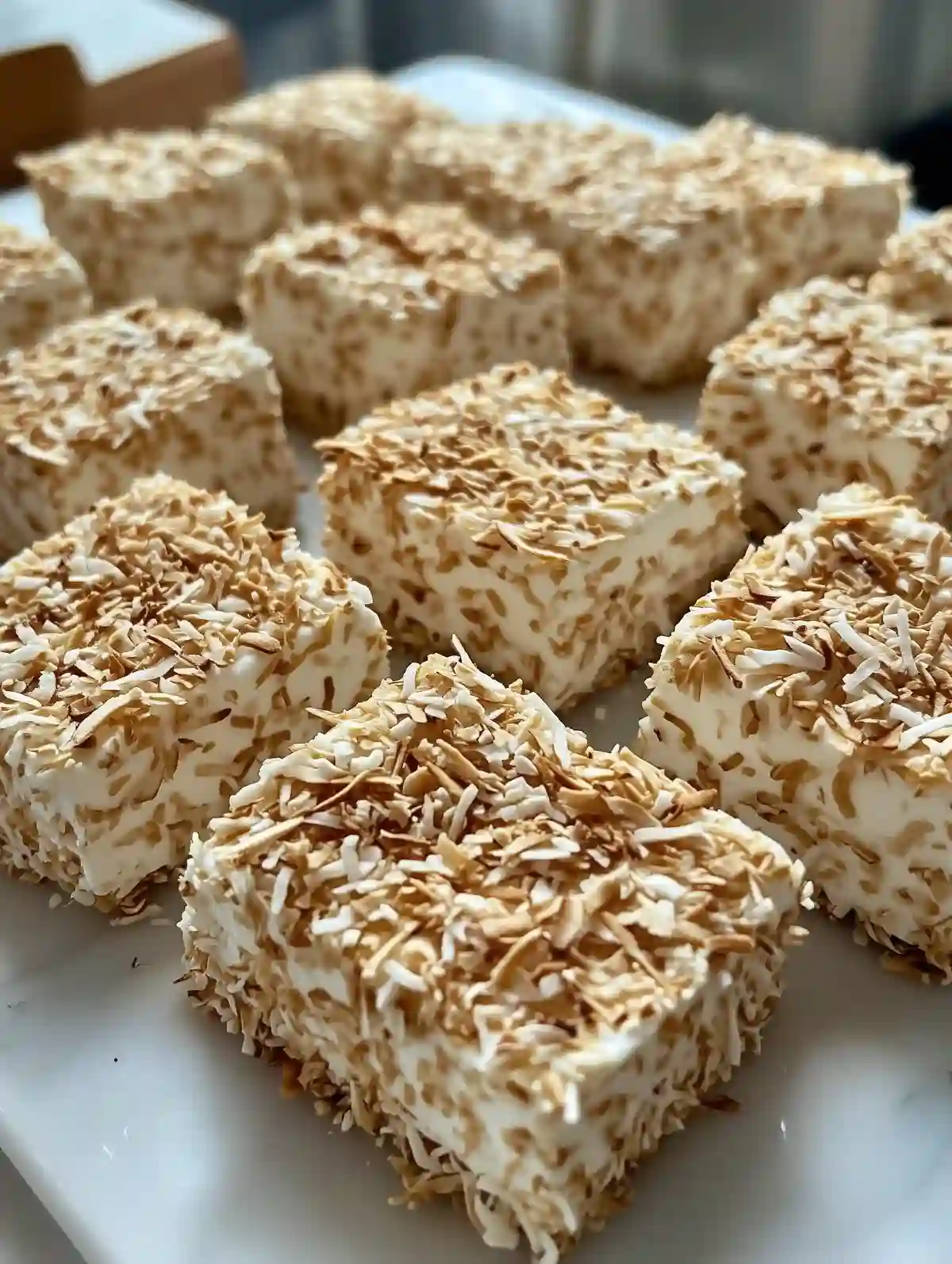 Square toasted coconut marshmallows on marble surface, stacked neatly