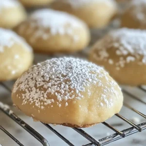 Pale golden cookies dusted with powdered sugar on a wire rack.