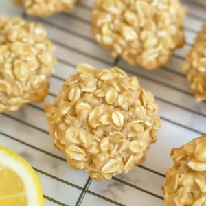 Golden oat cookies on a wire rack with a lemon wedge beside them.
