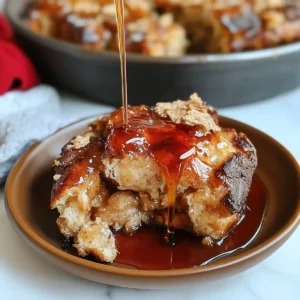 Golden-brown French toast casserole with syrup on a brown plate, with dish and marble surface