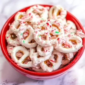 Bowl of white chocolate pretzels with peppermint bits on marble surface