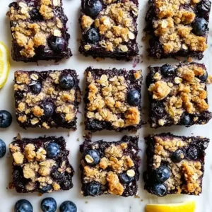 Blueberry dessert squares with oat crumble on a marble surface.