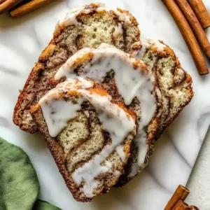 Cinnamon swirl banana bread slices with icing on a marble surface.