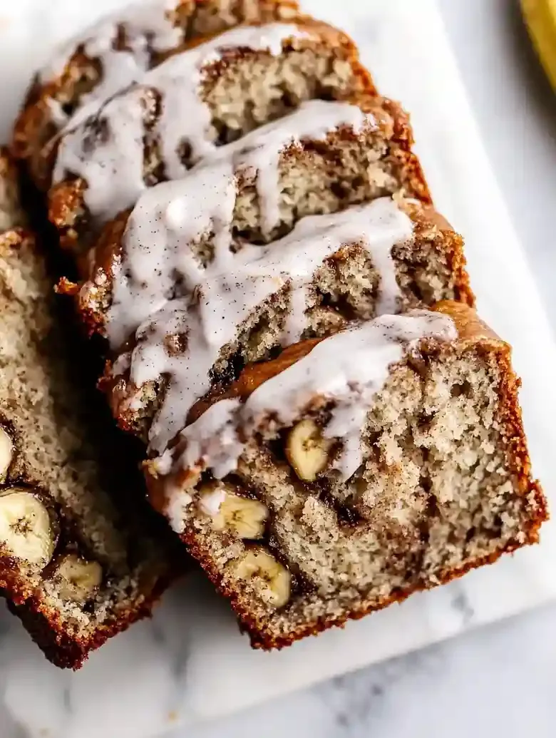 Cinnamon swirl banana bread slices on white marble surface.