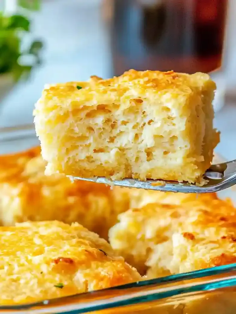 Golden-brown flaky biscuit lifted with tongs from glass dish.