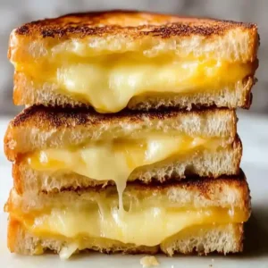 Stacked grilled cheese sandwich with melted cheddar and mozzarella on marble.
