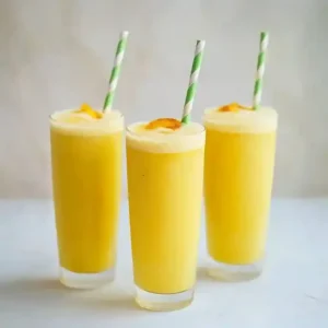 Three tall glasses of golden-yellow drinks with foam and striped straws.
