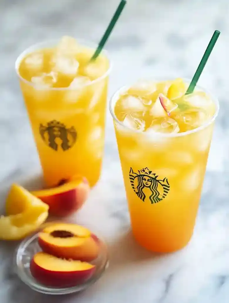 Two iced peach green tea lemonades with peach slices and lemon wedges.