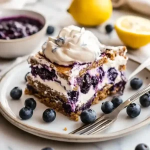 Lemon blueberry icebox cake slice on marble surface, garnished with blueberries.
