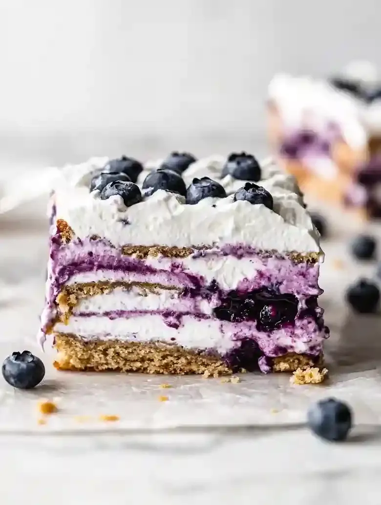 Lemon Blueberry Icebox Cake slice with graham crackers and fresh blueberries.