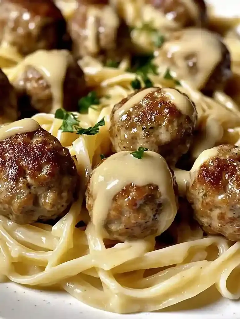Linguine pasta topped with golden-brown meatballs and garnished with parsley.