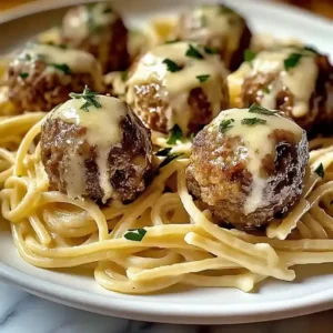 Linguine pasta with garlic butter meatballs and parsley on a white plate.