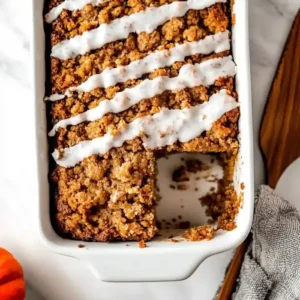 Freshly baked pumpkin coffee cake with crumbly topping and icing.