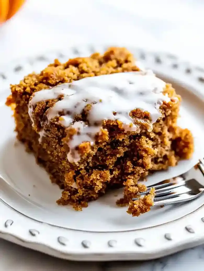 Pumpkin coffee cake slice on a decorative plate, fork nearby.
