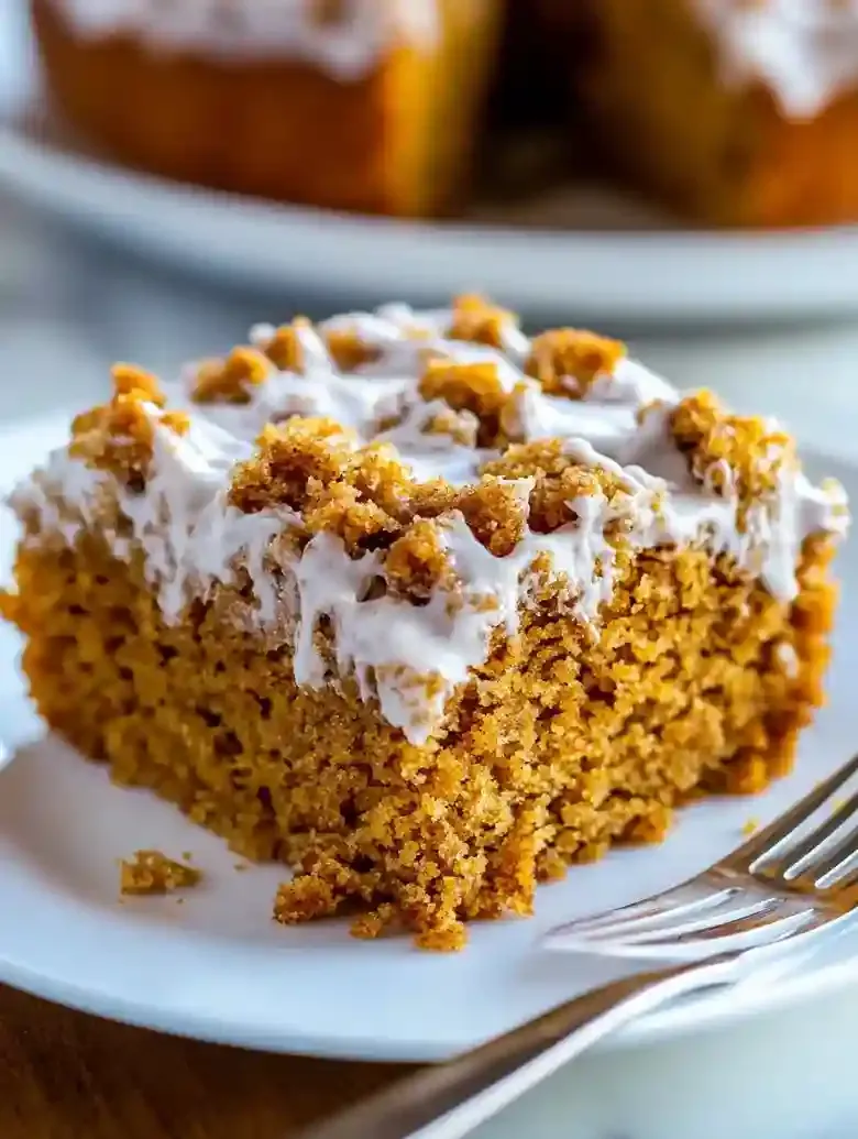 Pumpkin coffee cake slice with vanilla drizzle on a white plate.