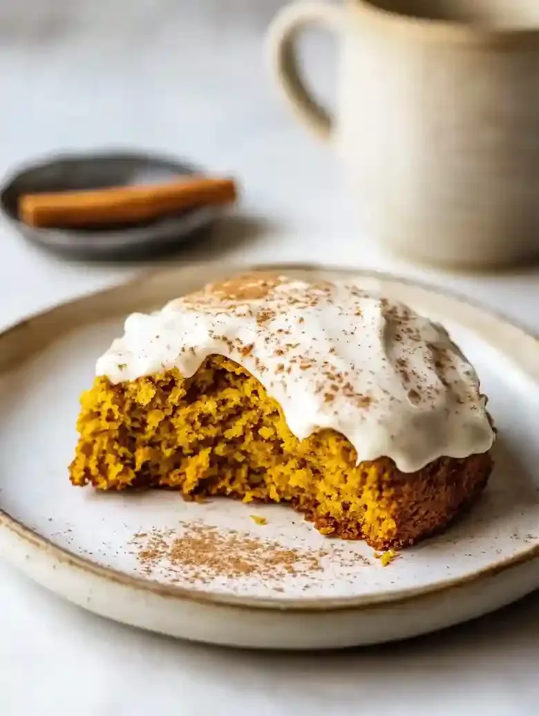 Pumpkin cream cheese scone on a rustic plate with cream cheese icing.