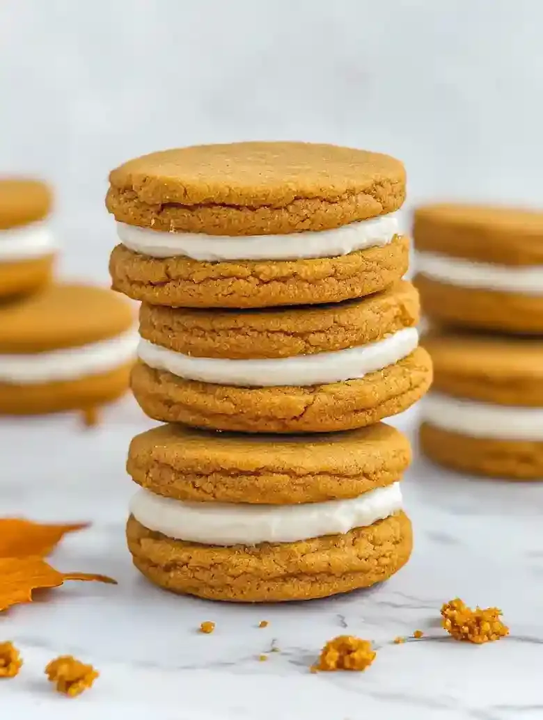 Stack of five pumpkin spice cookie sandwiches on a marble surface.