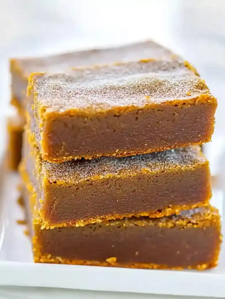 Stack of four pumpkin snickerdoodle blondies on a white plate.