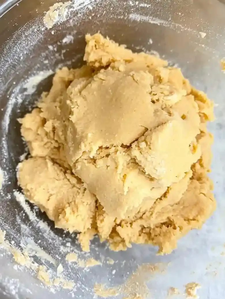 Mound of light beige cookie dough on white marble surface.