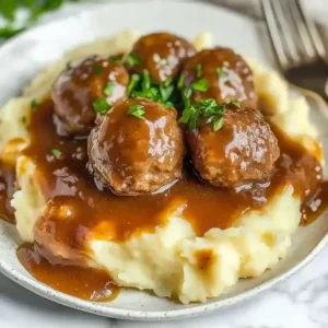 Salisbury steak meatballs on mashed potatoes with brown gravy and parsley.