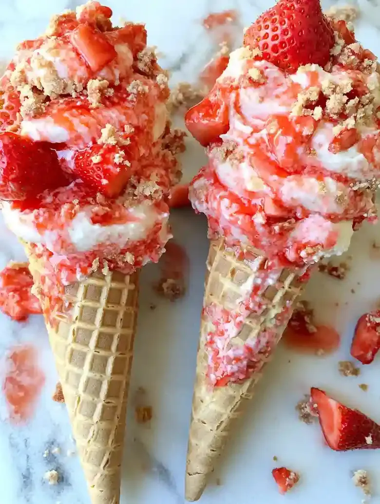 Waffle cones filled with cheesecake, topped with strawberries and glaze.