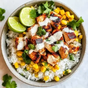 Bowl of jasmine rice topped with grilled chicken, corn, and lime wedges.