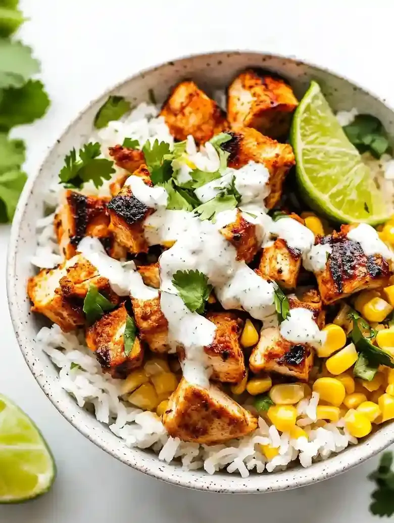 Street corn chicken rice bowl with grilled chicken, corn, and lime wedge.
