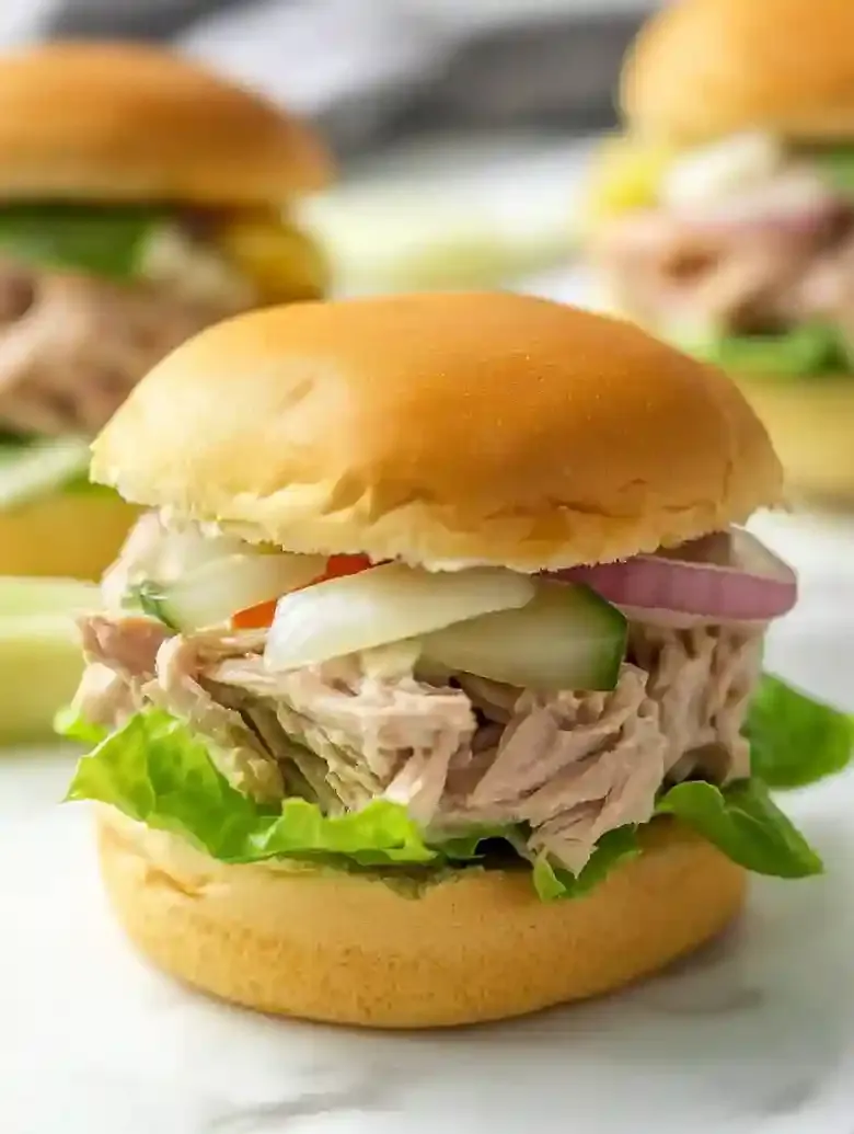 Tuna salad slider with pepper jack cheese and lettuce on marble surface.