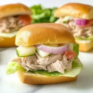 Close-up of a slider with chicken tender, tuna salad, cheese, and lettuce.