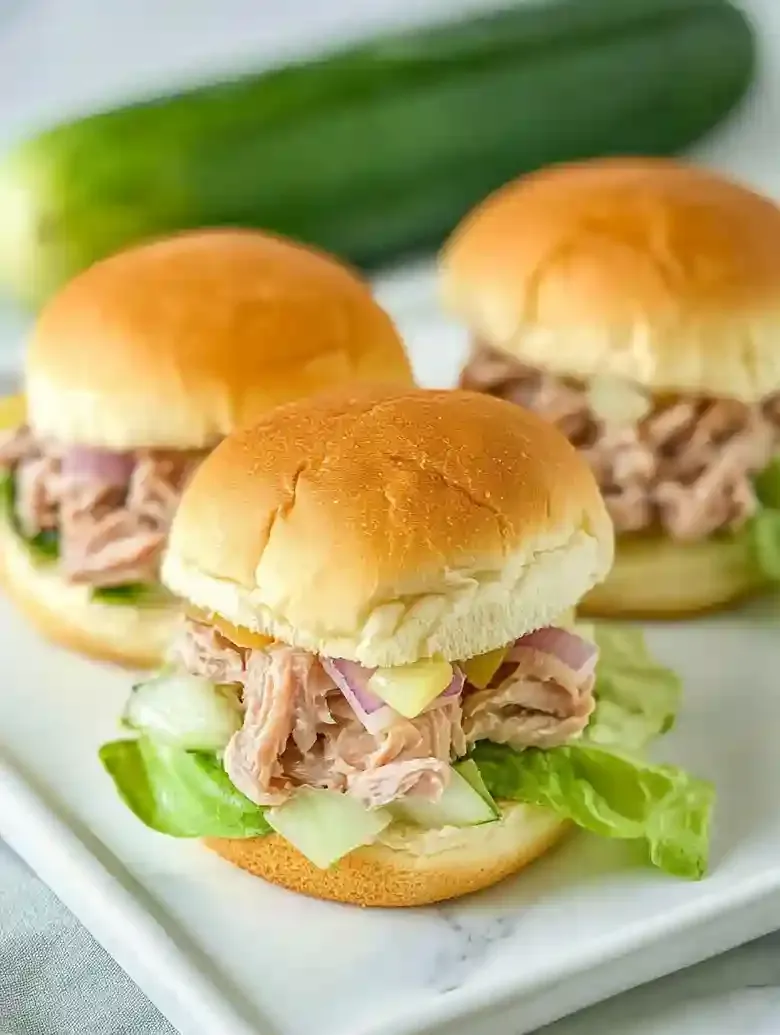 Three tuna salad sliders on toasted buns with lettuce and pepper jack cheese.