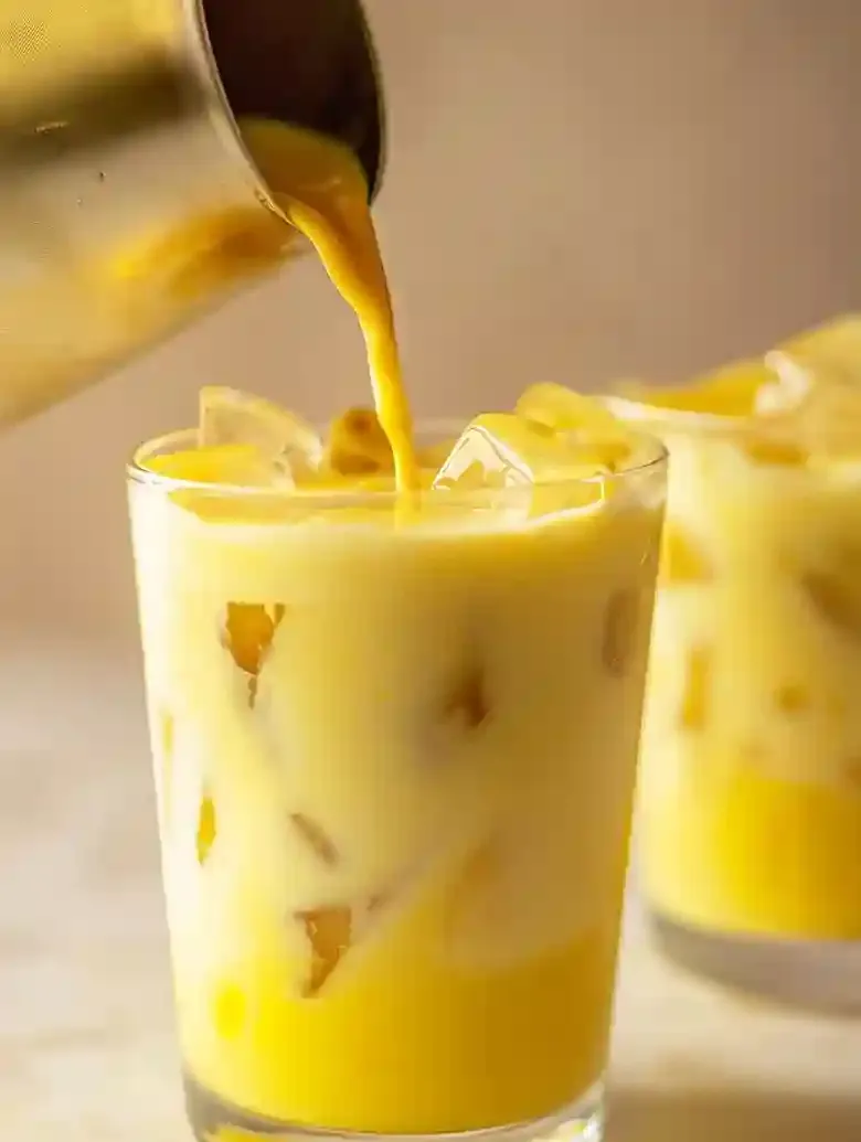 Turmeric iced latte poured into a glass filled with ice cubes.