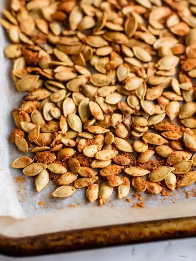 Roasted pepitas on a marble baking sheet with gray veining.