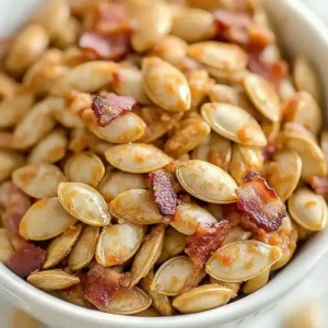 Bowl of toasted pumpkin seeds mixed with crispy bacon pieces.