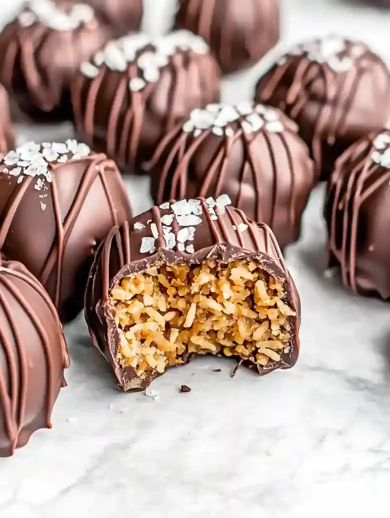 Chocolate-covered peanut butter balls with sea salt, one cut in half.